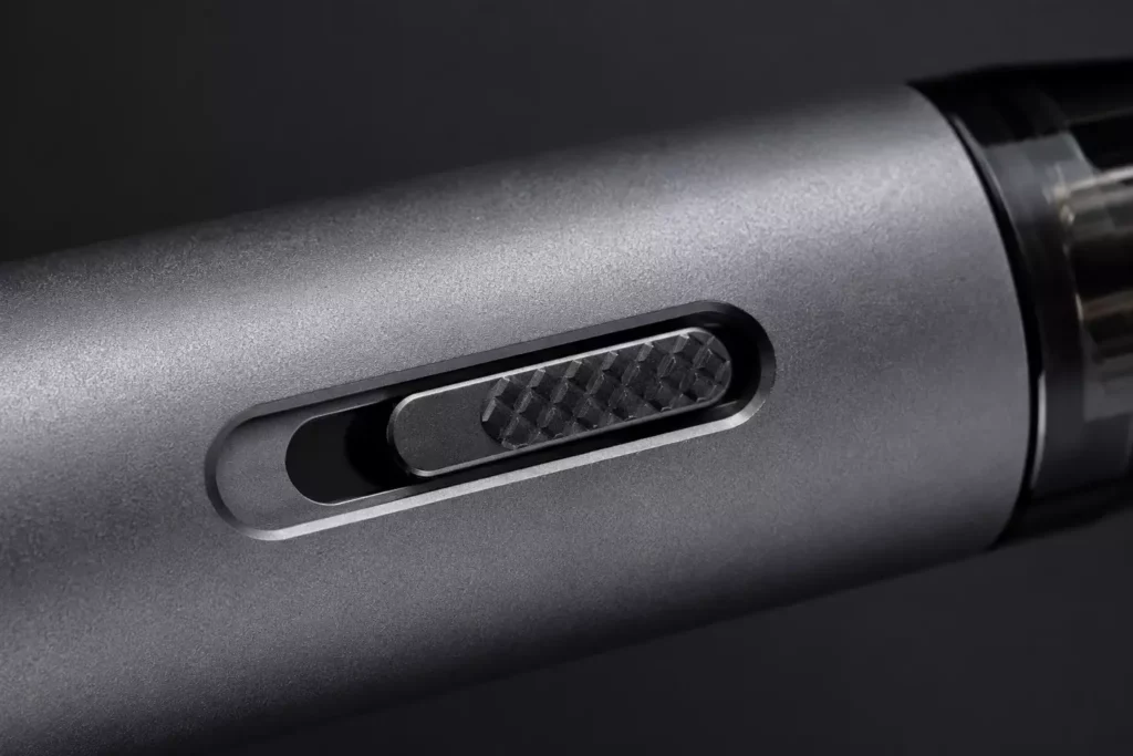 Close-up technical view of a mechanical airflow adjustment slider toggle built into the side of a premium gunmetal vape pod kit.