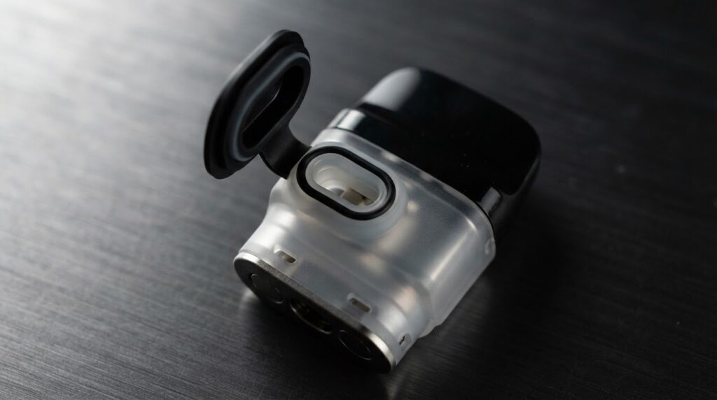 Vaporesso XROS 5 Mini top-fill pod open fill port close-up showing silicone seal and fill channel on brushed metal surface