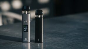 Vaporesso XROS 5 vs XROS 5 Mini side by side on slate surface showing screen and no-screen design difference